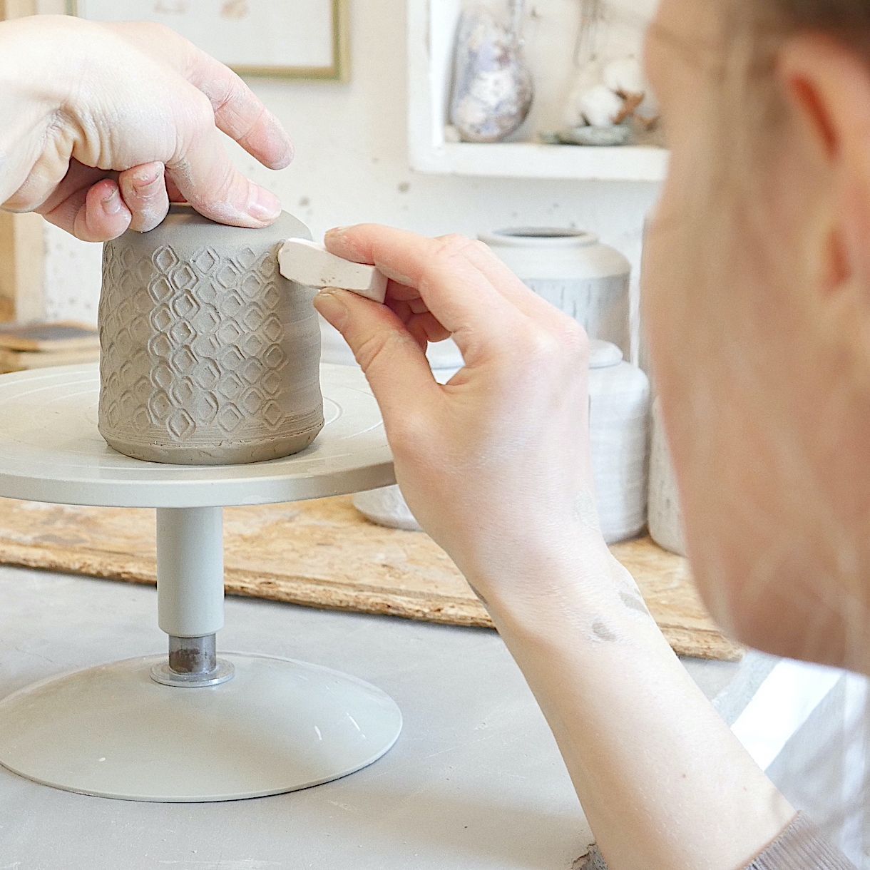 Pernille Buch dekorerer lågkrukke med stempel i keramikværksted 