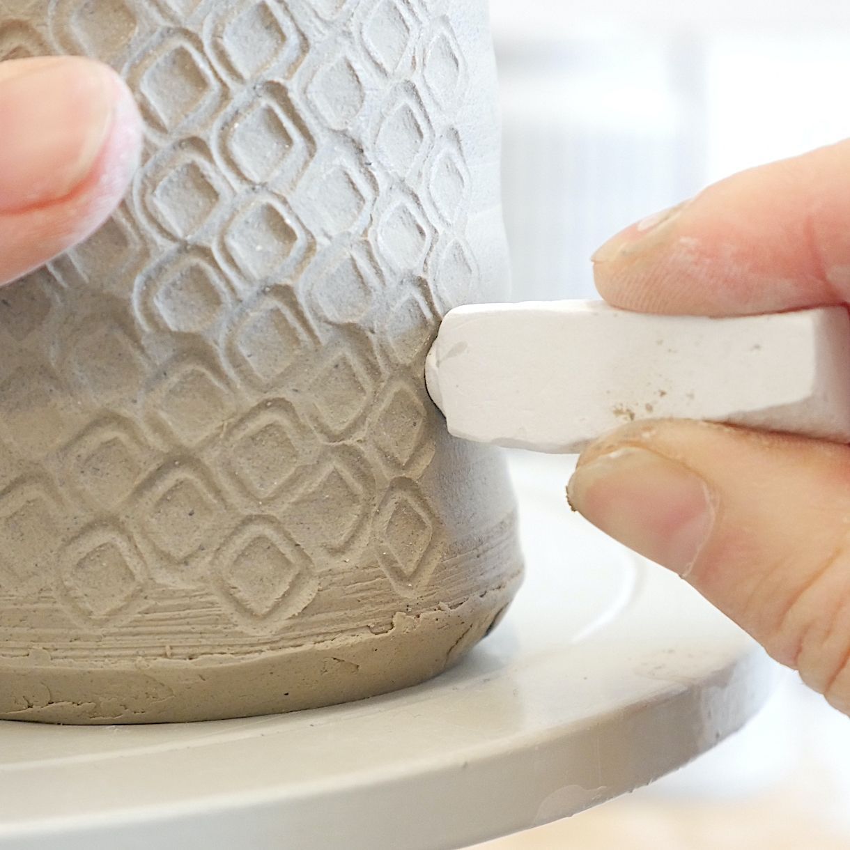 Keramiker Pernille Buch laver struktur på lågkrukke i sit keramikværksted